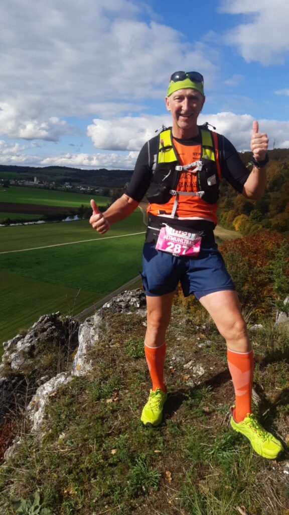 Trailläufer steht vor Felskante, freut sich