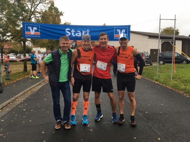 Läufer stehen aufgereiht zum Gruppenfoto vor Start-Banner