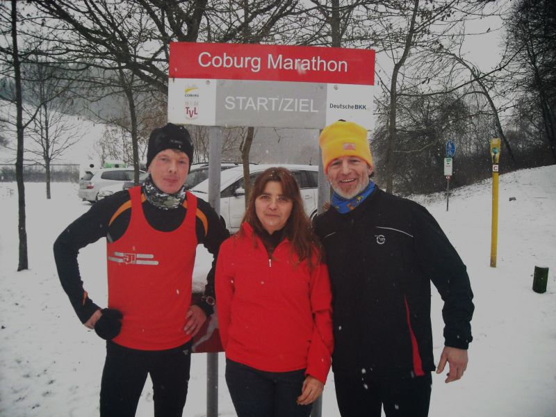Zwei Läufer und eine Läuferin vor dem Schild des Coburg Marathons