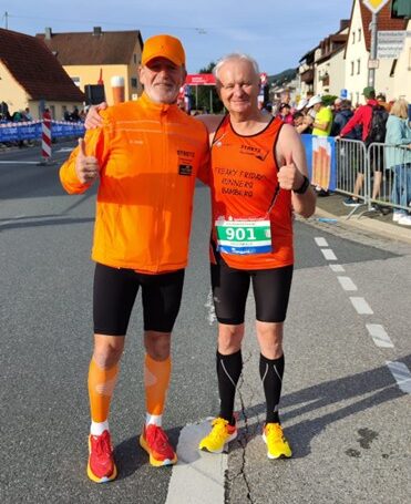 Zwei Läufer posieren mit Daumen hoch im Startbereich