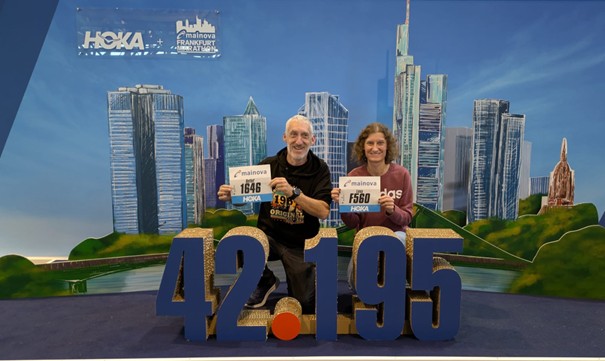 Zwei Läufer vor Poster mit Startnummern in der Hand