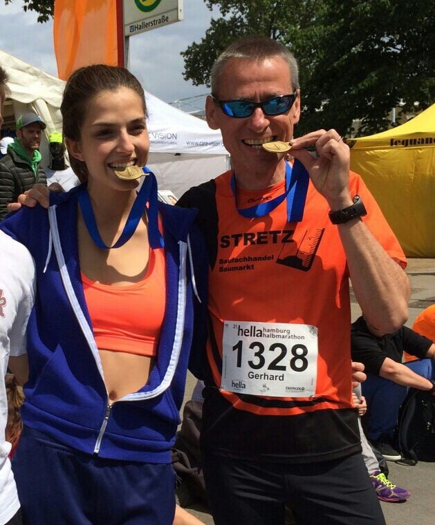 Läufer und Läuferin nach dem Lauf mit Medaille im Mund