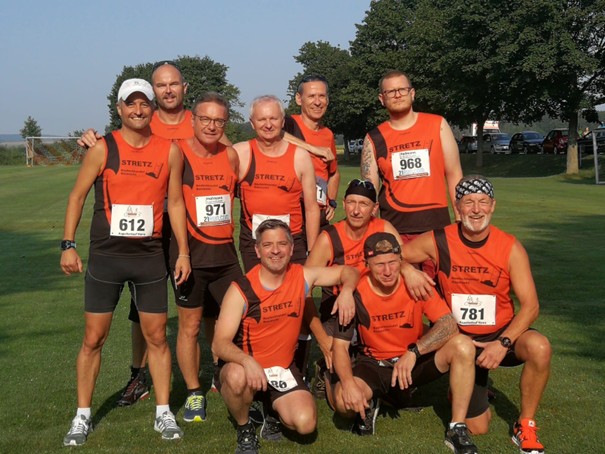 Läufer in orangenem Trikot in der Natur, Gruppenbild