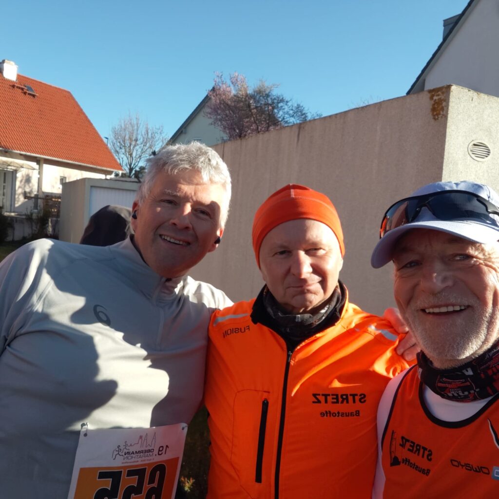 Drei Läufer machen Selfie, blauer Himmel im Hintergrund
