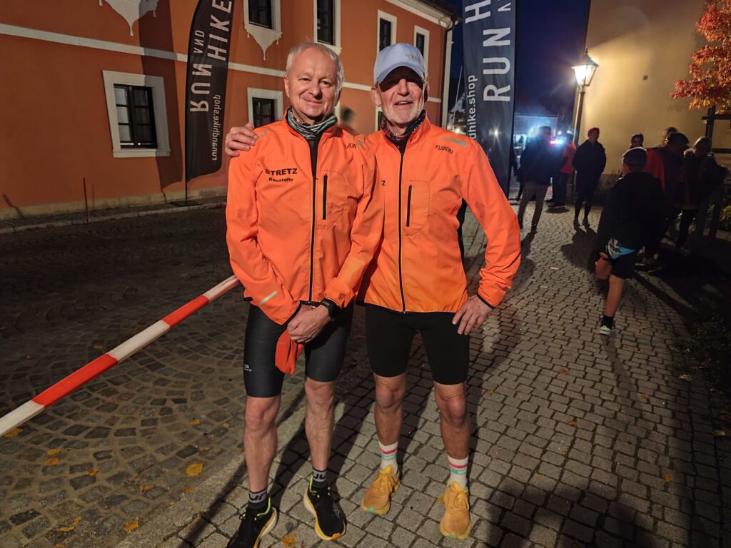 Zwei Läufer im Licht, mit organenen Jacken