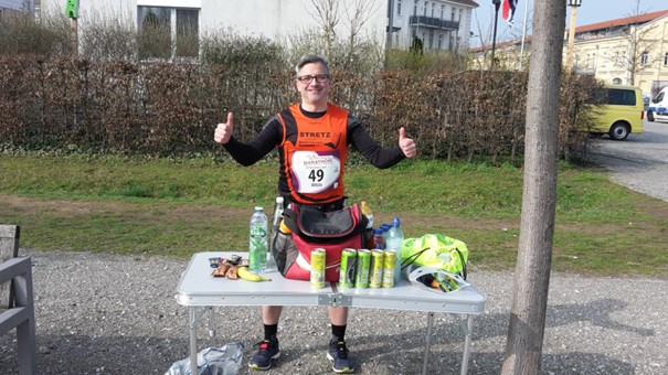 Läufer steht hinter Tisch mit Verpflegung zum Laufen