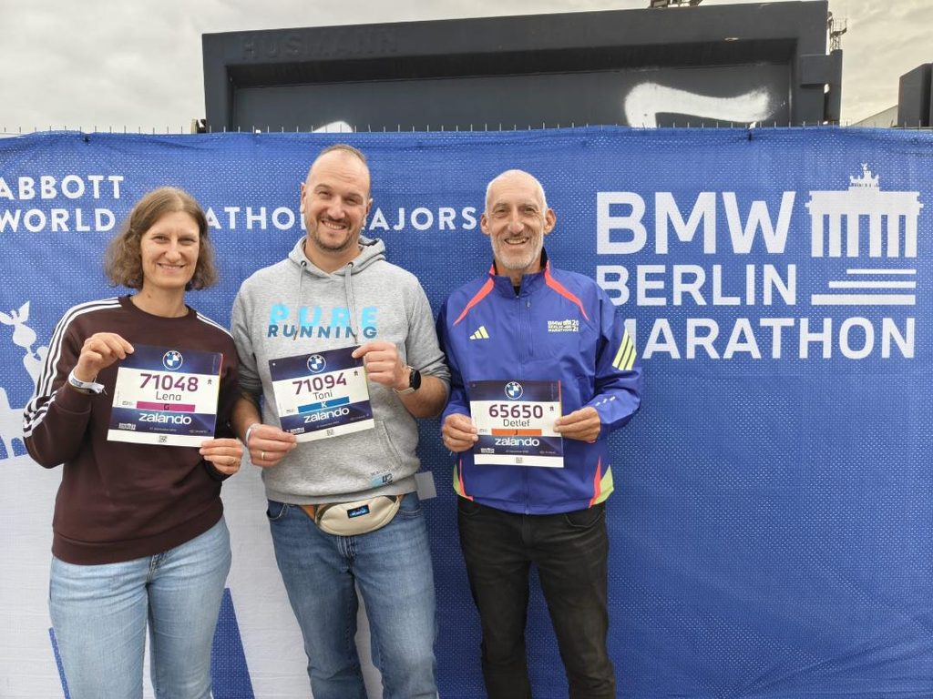 3 Läufer vor dem Banner des Berlin-Marathons 2026